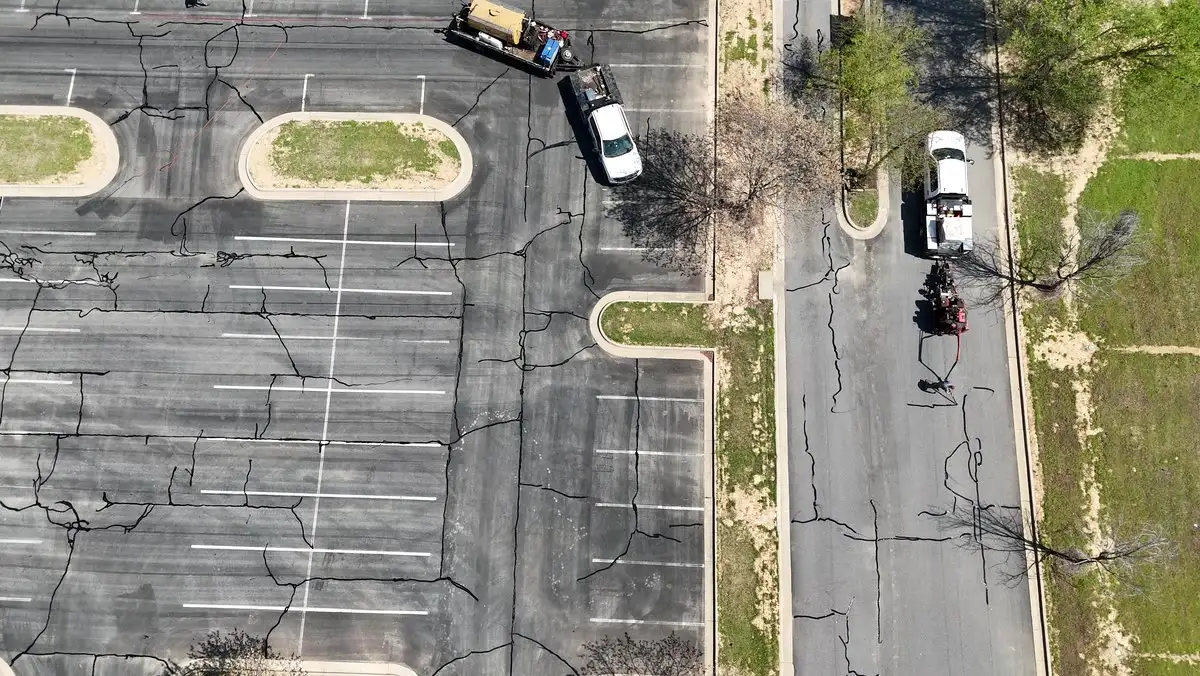 An Arkansas Pavement crew member brushing sealer along the edge of a parking lot, keeping the line clear of the curb