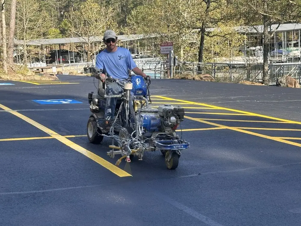 A crew member riding a line striper, laying a yellow stall line at Hot Springs