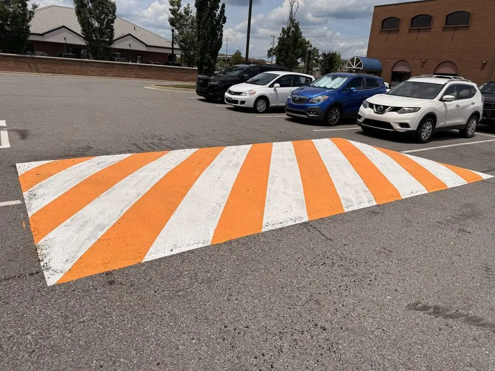 A newly painted orange and white speed bump in a busy parking lot