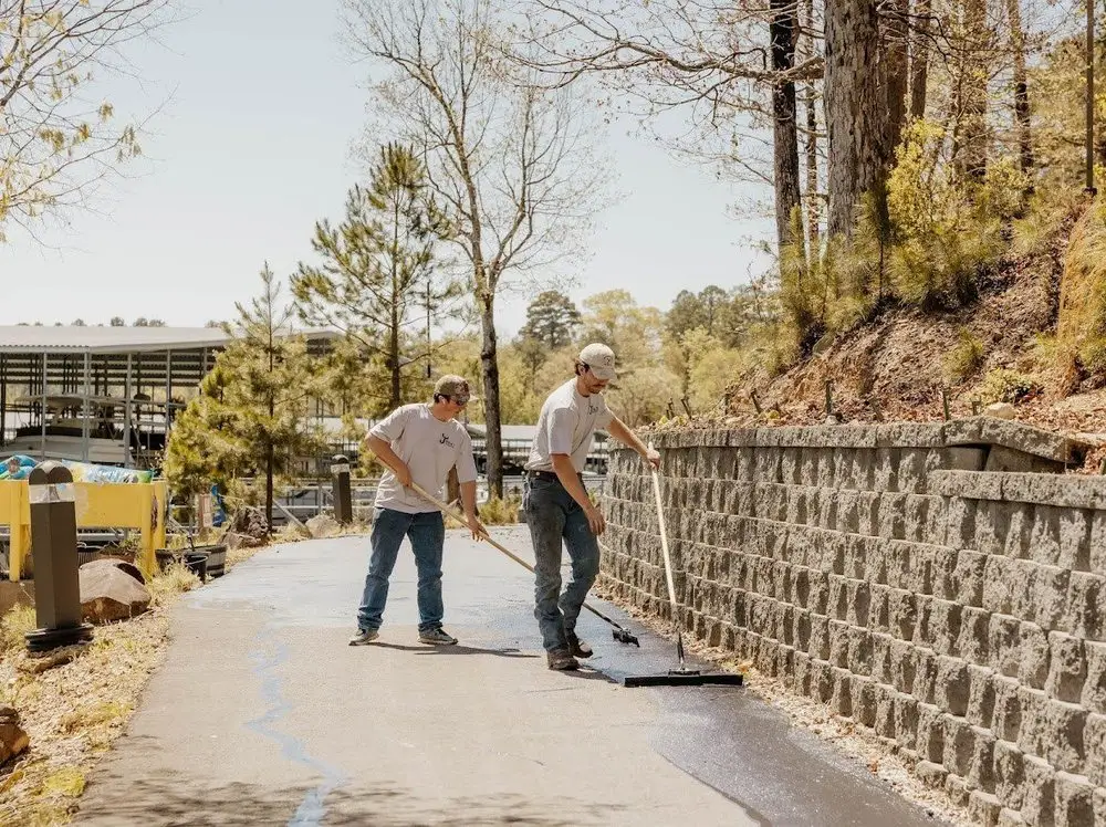 Two crew members working a squeegee along a retaining wall