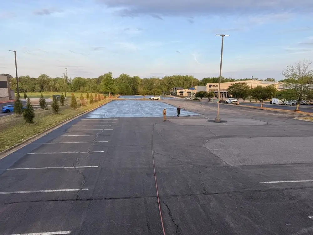 A large lot part way through sealcoating, the finished half darker than the rest