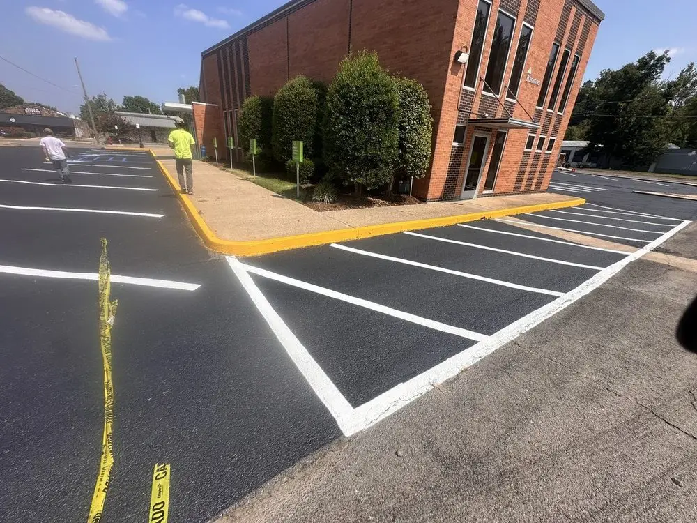 A crew member in high visibility gear striping beside a brick building