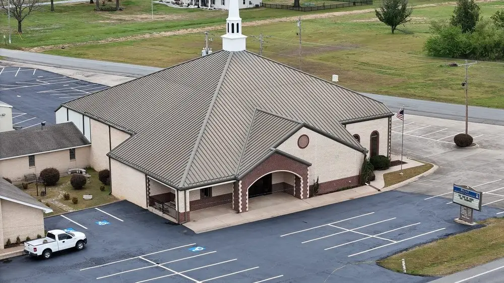 Aerial view of a brick church with a white steeple and its finished lot