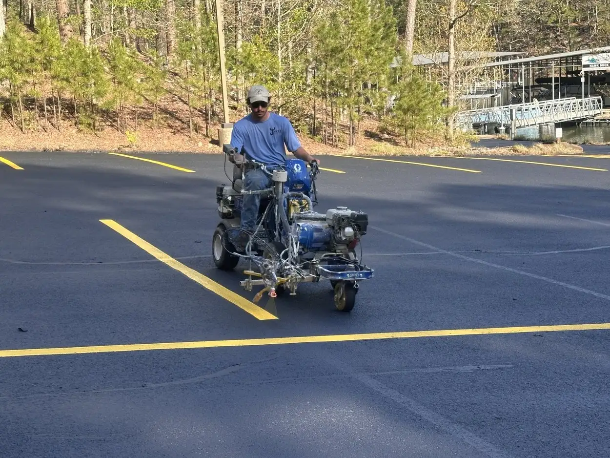 An Arkansas Pavement crew member riding a line striper, laying a fresh yellow stall line